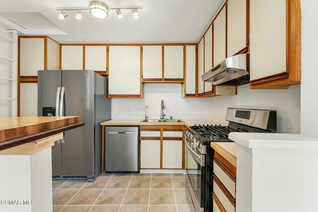 kitchen with light tile patterned floors, sink, stainless steel appliances, and white cabinetry