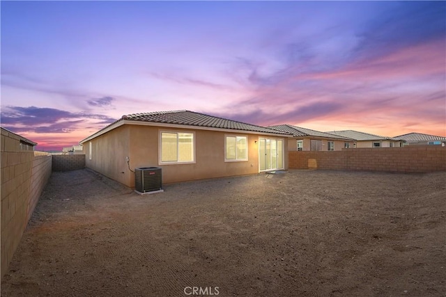 back house at dusk featuring central AC unit