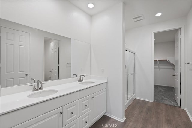 bathroom with a shower with shower door, hardwood / wood-style floors, and vanity