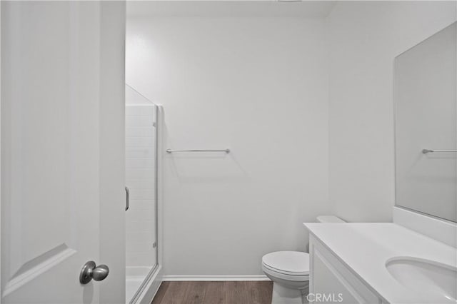 bathroom featuring hardwood / wood-style flooring, toilet, walk in shower, and vanity