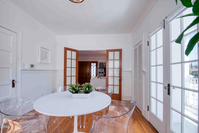 dining space with french doors, ornamental molding, and hardwood / wood-style flooring