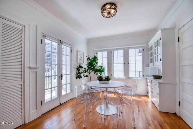 dining area with crown molding, light hardwood / wood-style flooring, and french doors