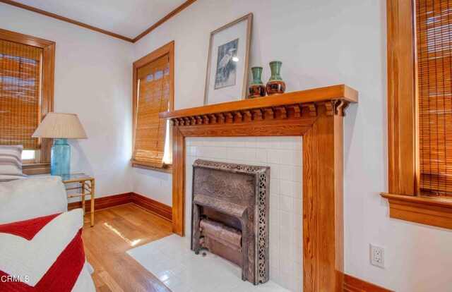 living room with a tile fireplace, crown molding, and light hardwood / wood-style flooring