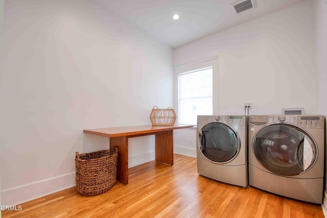 washroom with washing machine and dryer and light hardwood / wood-style floors