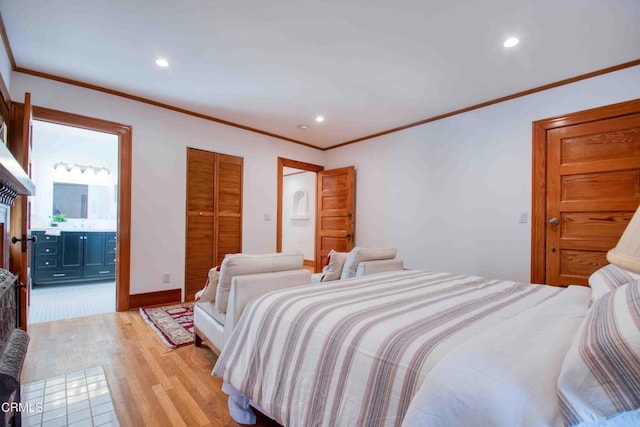 bedroom featuring a closet, crown molding, light hardwood / wood-style floors, and ensuite bath