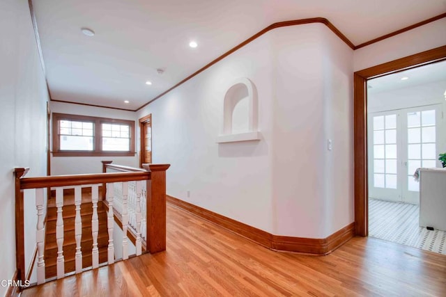 corridor with ornamental molding, light hardwood / wood-style floors, and french doors