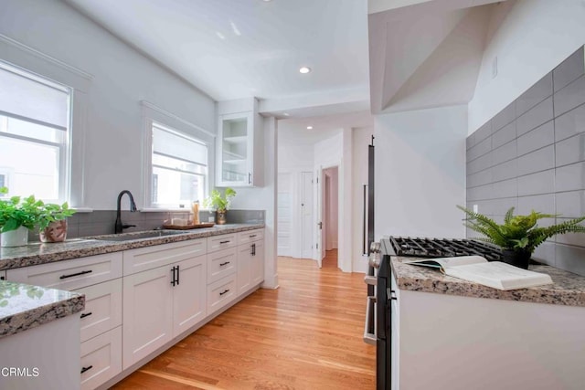 kitchen featuring white cabinets, light wood-type flooring, sink, and light stone counters