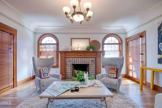 living room with an inviting chandelier, a wealth of natural light, light hardwood / wood-style floors, and a tile fireplace