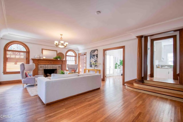 living room featuring light wood-type flooring, a wealth of natural light, an inviting chandelier, and a tile fireplace