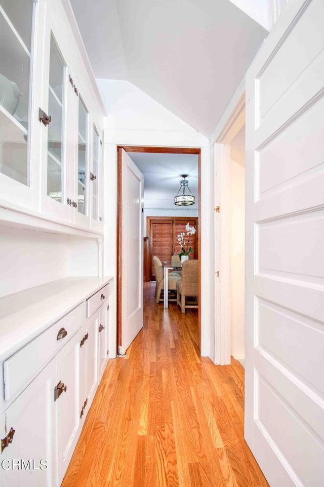 hallway featuring lofted ceiling and light hardwood / wood-style flooring