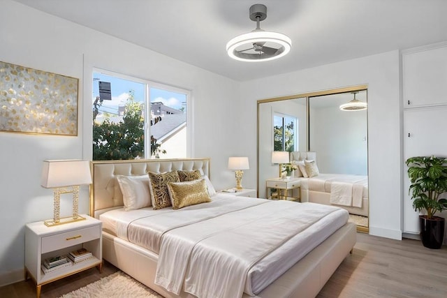 bedroom with ceiling fan, a closet, and light hardwood / wood-style flooring