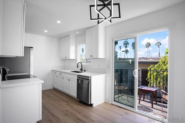 kitchen featuring sink, white cabinetry, light hardwood / wood-style flooring, dishwasher, and a barn door