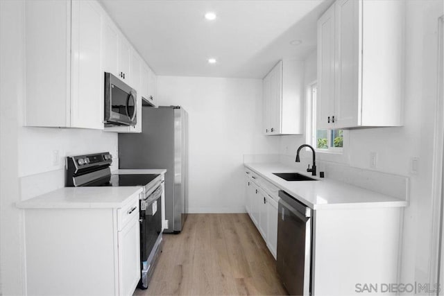 kitchen featuring stainless steel appliances, white cabinetry, sink, and light hardwood / wood-style flooring