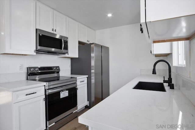 kitchen with stainless steel appliances, sink, and white cabinets