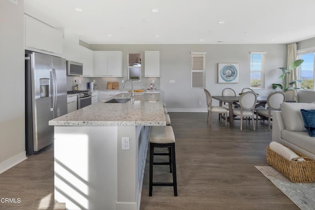 kitchen featuring white cabinets, appliances with stainless steel finishes, dark hardwood / wood-style flooring, sink, and a center island with sink