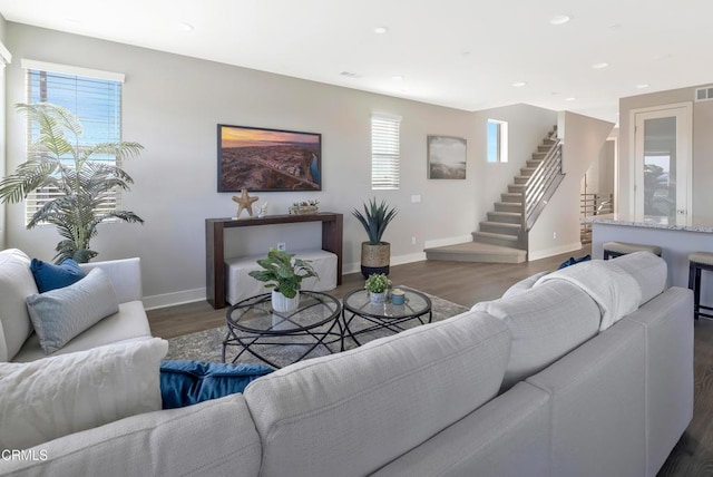 living area with wood finished floors, baseboards, and stairs