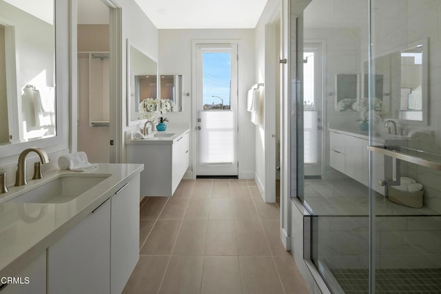 bathroom with a stall shower, two vanities, a sink, and tile patterned floors