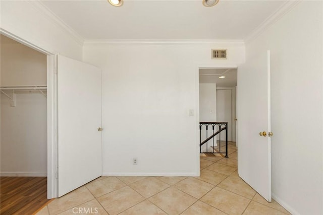 unfurnished bedroom featuring a closet, crown molding, and light tile patterned flooring