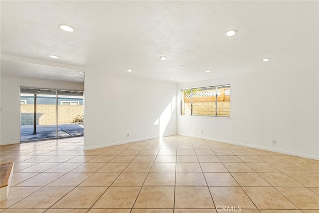 empty room featuring plenty of natural light, light tile patterned floors, and crown molding