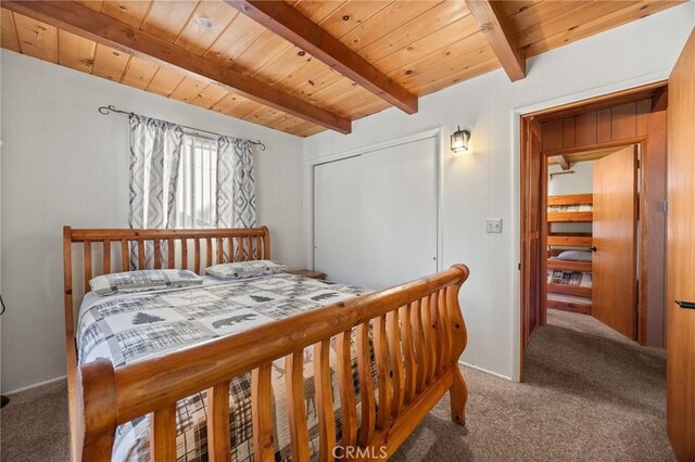 bedroom featuring a closet, carpet flooring, wood ceiling, and beam ceiling