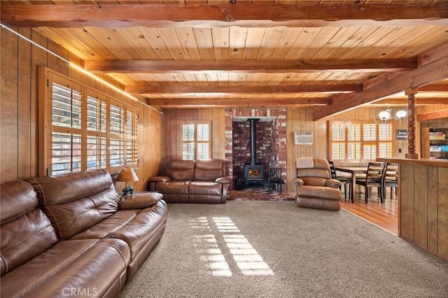 carpeted living room featuring a wood stove, beamed ceiling, and wooden walls