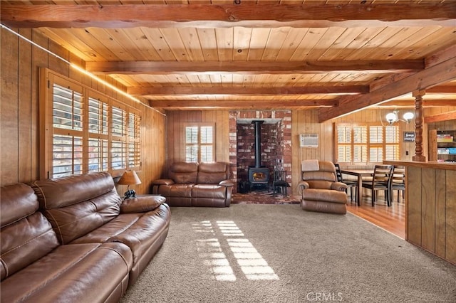 carpeted living room with beamed ceiling, wood walls, wooden ceiling, and a wood stove