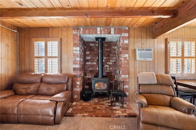 carpeted living room featuring beamed ceiling, wooden walls, a wood stove, and a wall mounted air conditioner