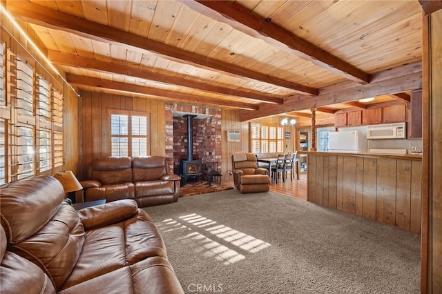 living room with wood ceiling, carpet floors, a wood stove, wood walls, and beam ceiling