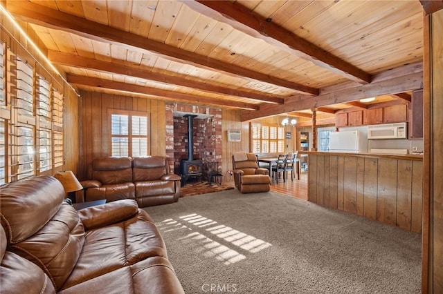 living room featuring a wood stove, wooden ceiling, wooden walls, and beam ceiling