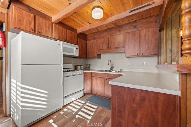 kitchen with white appliances, brown cabinets, a sink, and beam ceiling