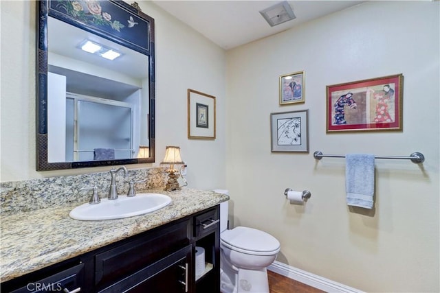 bathroom featuring a shower with shower door, toilet, and vanity