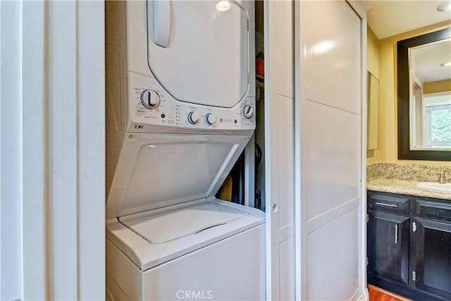 clothes washing area with sink and stacked washer and clothes dryer