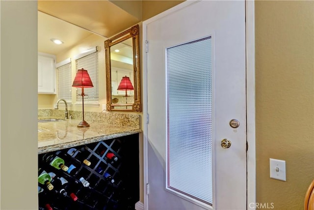 interior space featuring light stone counters, sink, and white cabinets