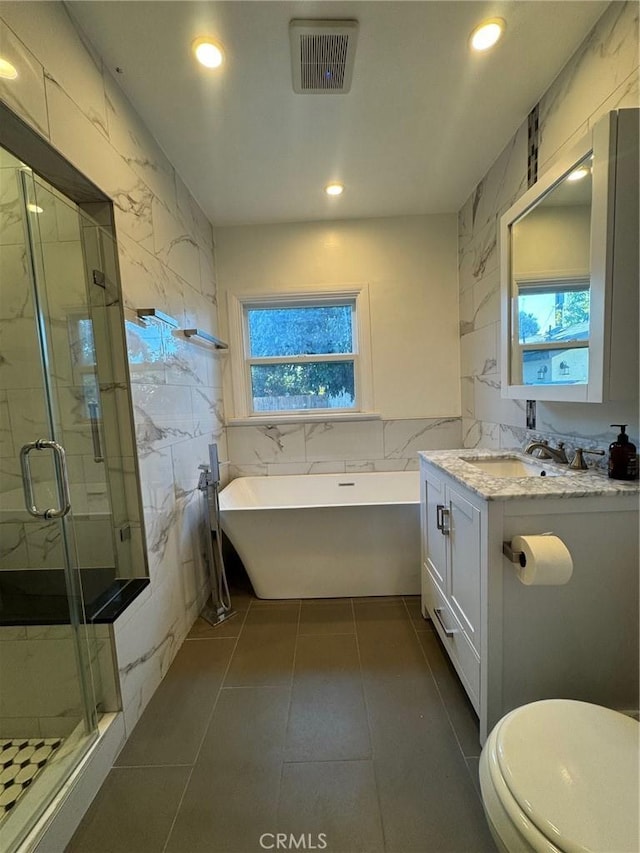 full bathroom with toilet, vanity, tile walls, tile patterned floors, and plus walk in shower