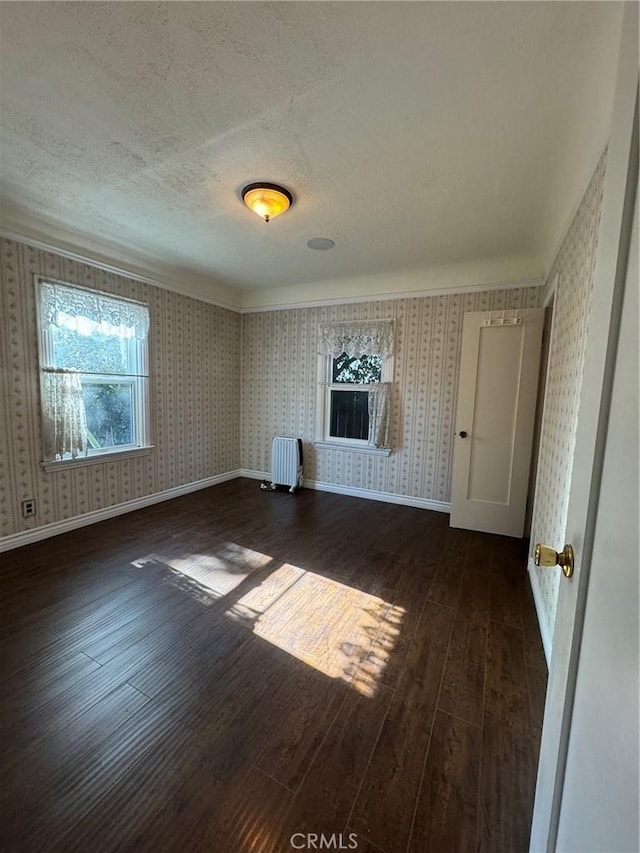 unfurnished living room featuring radiator, dark hardwood / wood-style floors, and a textured ceiling