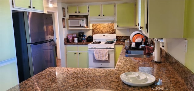 kitchen featuring sink, extractor fan, dark stone counters, and white appliances