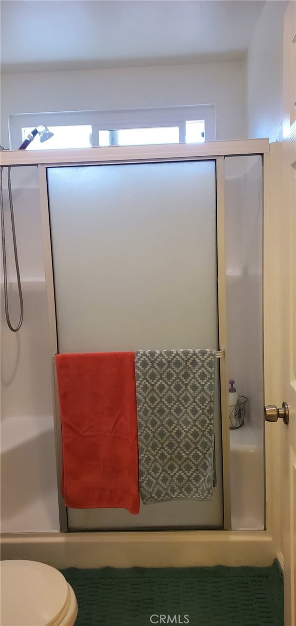 bathroom with toilet and a shower with shower door