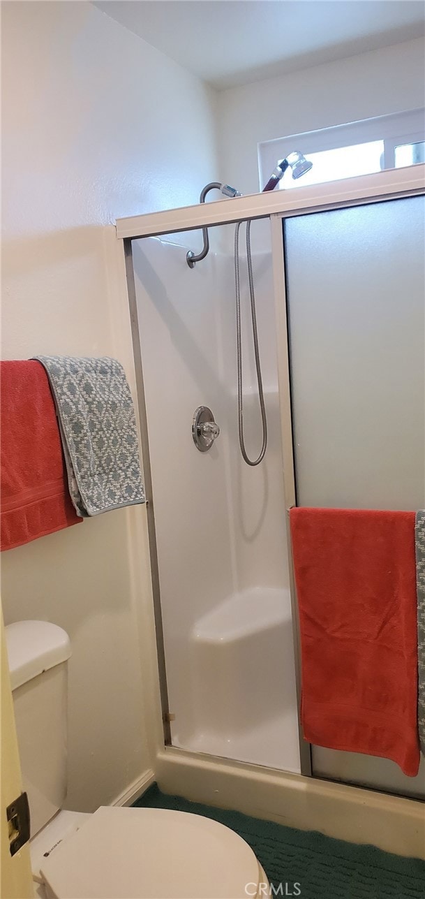 bathroom featuring an enclosed shower and toilet