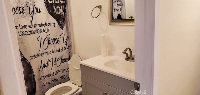 bathroom featuring toilet, vanity, and walk in shower