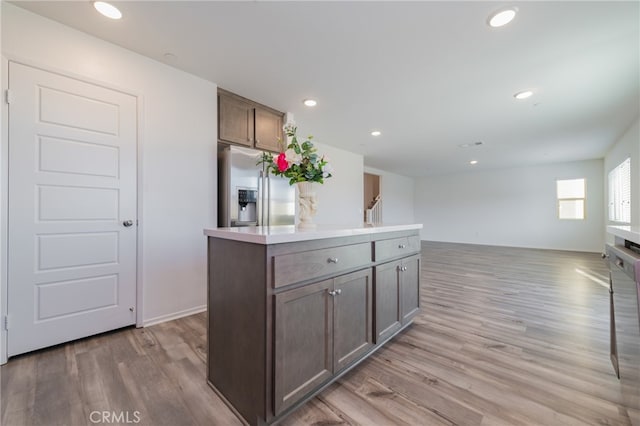 kitchen featuring stainless steel refrigerator with ice dispenser, dark brown cabinets, light hardwood / wood-style floors, and a kitchen island