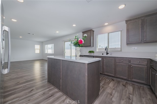 kitchen with sink, dark brown cabinetry, dark hardwood / wood-style floors, and a center island