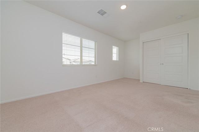 unfurnished bedroom featuring a closet and light colored carpet