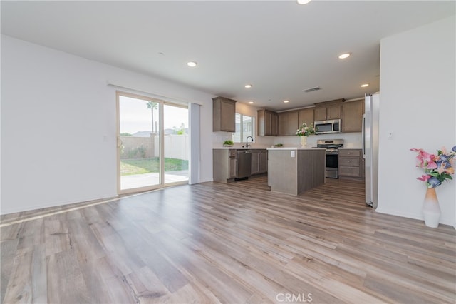 kitchen with light hardwood / wood-style floors, sink, stainless steel appliances, and a center island