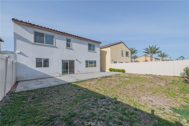 back of property with a lawn and a patio