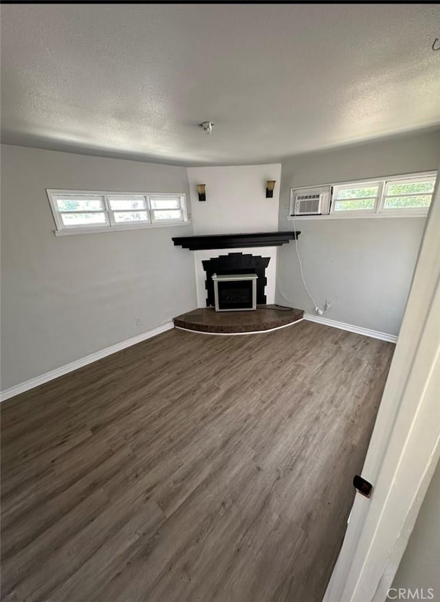 unfurnished living room featuring a textured ceiling and dark hardwood / wood-style floors