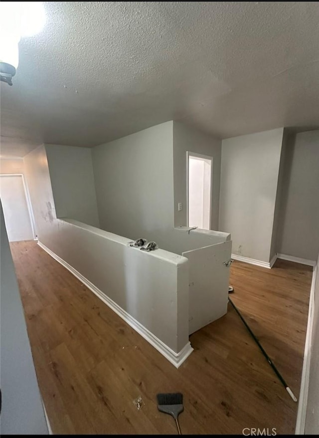 hallway featuring a textured ceiling and hardwood / wood-style flooring