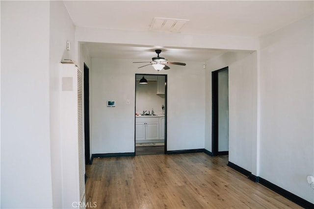 empty room with ceiling fan, sink, and wood-type flooring