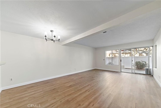 spare room with beamed ceiling, hardwood / wood-style floors, and a notable chandelier