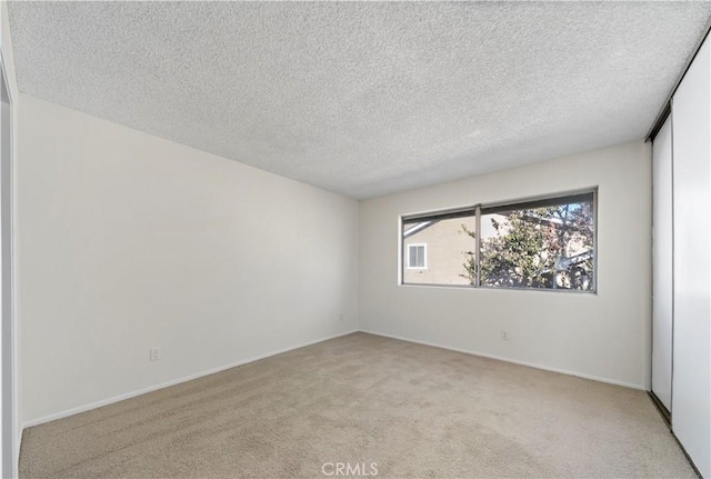 spare room with light carpet and a textured ceiling