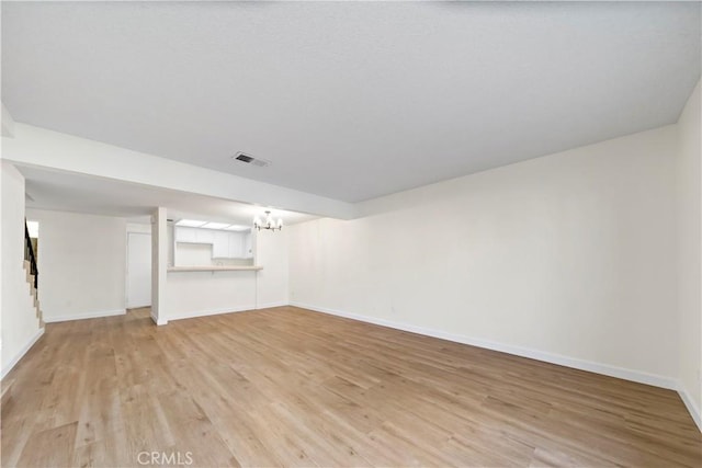 unfurnished living room with a chandelier and light wood-type flooring